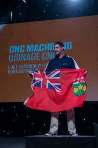 A proud Tyler stands on the podium, holding the Ontario flag