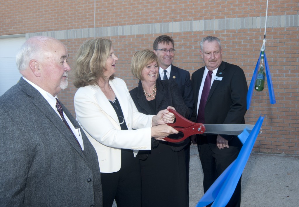 Dignitaries cutting a ribbon with a giant pair of scissors