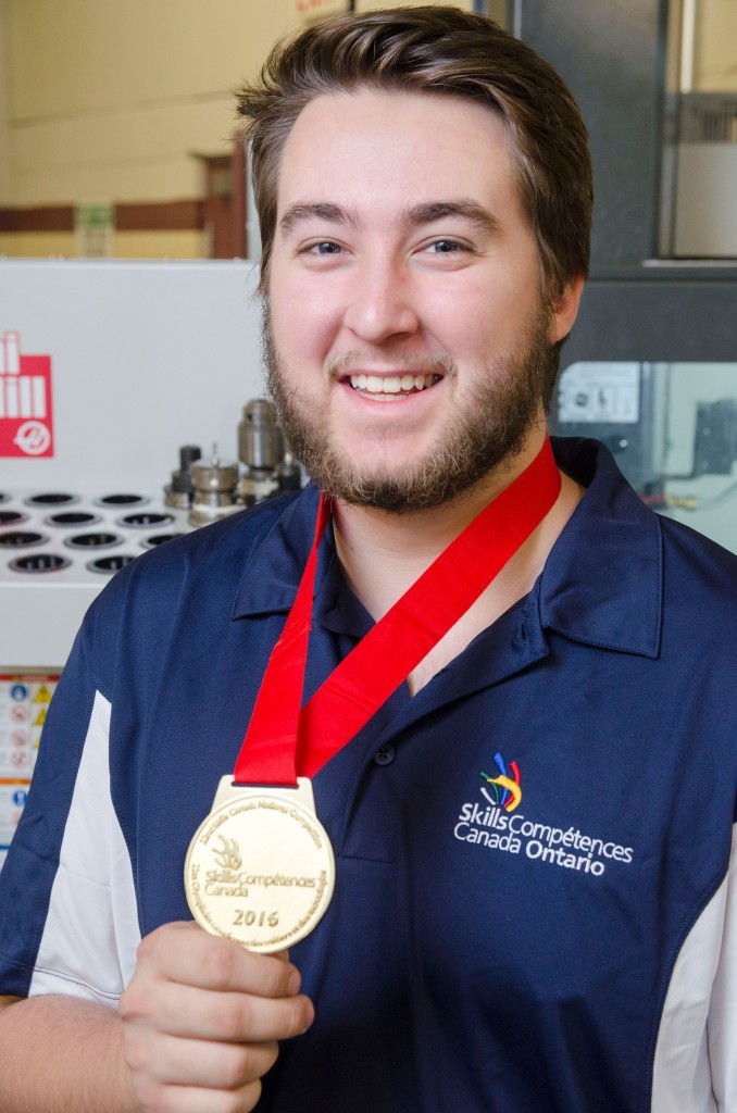 Eng Tech male student (Jonathan Adair) holding the gold medal he won at the Skills Canada competition.