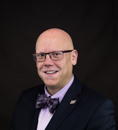 Man in suit, purple shirt and bowtie