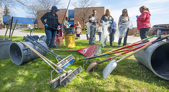Staff and students preparing for campus cleanup - rakes in the foreground