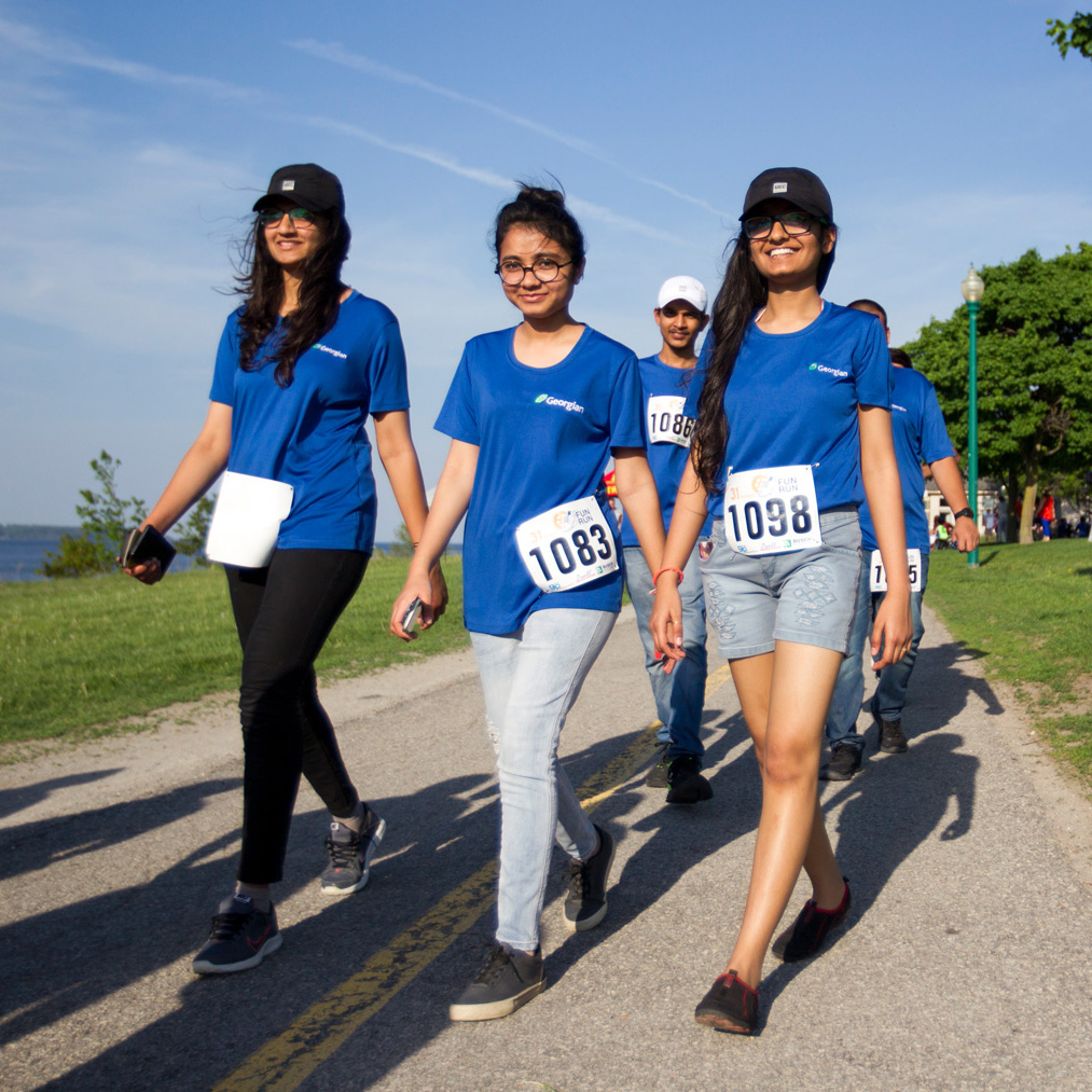 Three female students representing team Georgian at the Rotary Fun Run event along Barrie's waterfront