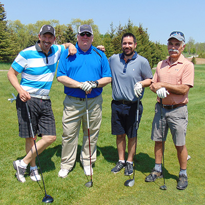 four men standing on a golf course with golf clubs at the 2018 Georgian Golf Classic