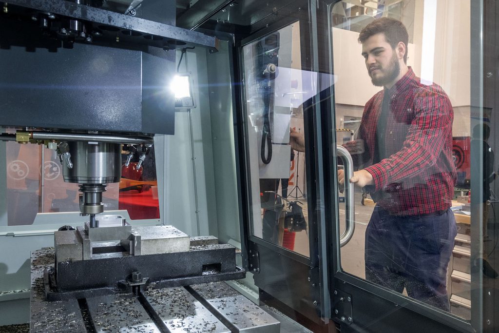 A man looks through the glass door of machining equipment used in the Advanced Technology Centre at Georgian College.