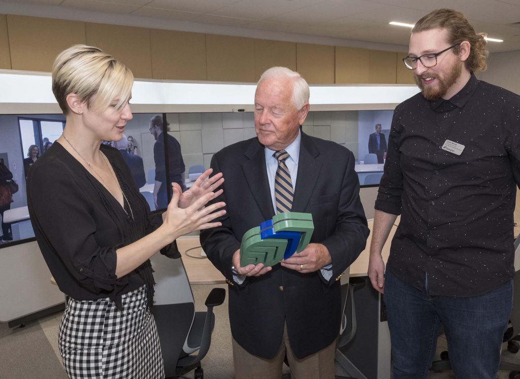 Students Virginia Barlow (left) and Connor Minielly (right) show Peter Moore an accelerator they made using a 3-D printer in the changemaker space.