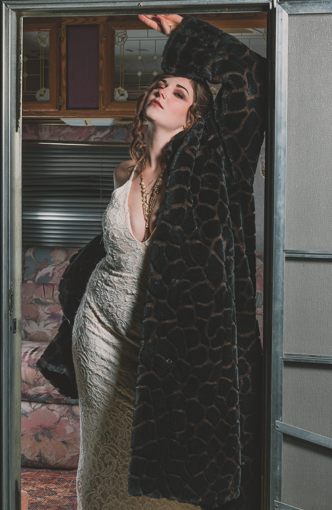 Photo of a woman standing seductively in a door with a dress and a leopard coat on