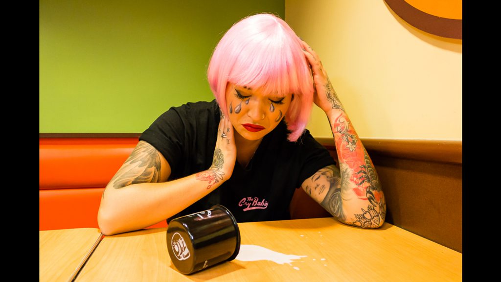 Girl with pink hair and tattoos crying with spilled milk