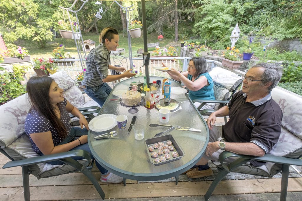 Four people sitting on a back deck eating