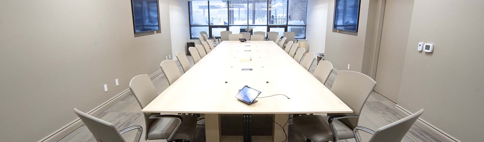 A empty, rectangular boardroom table with chairs