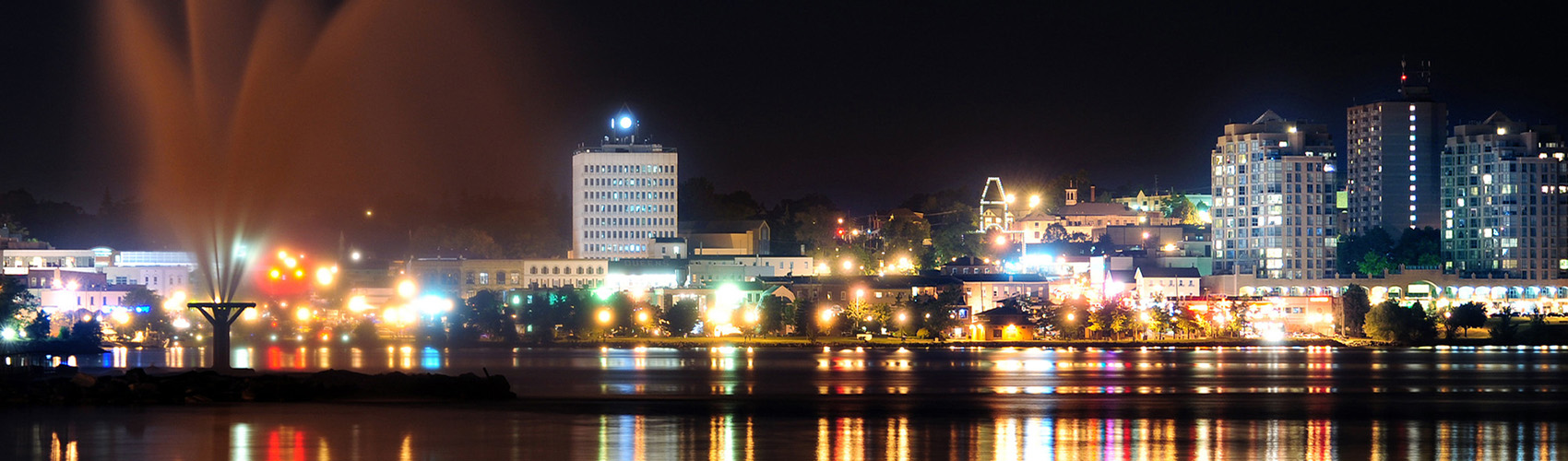 A view of the City of Barrie skyline, lit up at night, with Lake Simcoe in the foreground