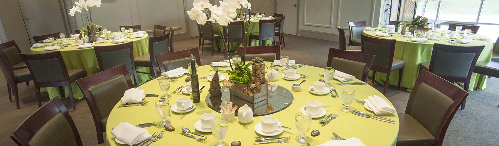 A dining table set for dinner service, with a green table cloth and an orchid flower centre piece