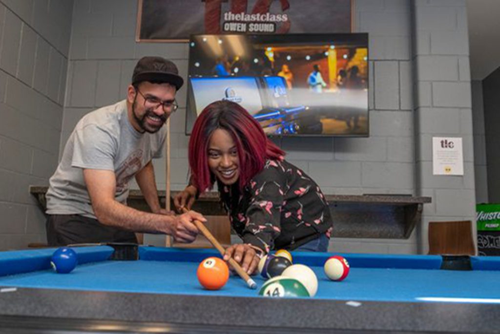 Male and female student playing pool