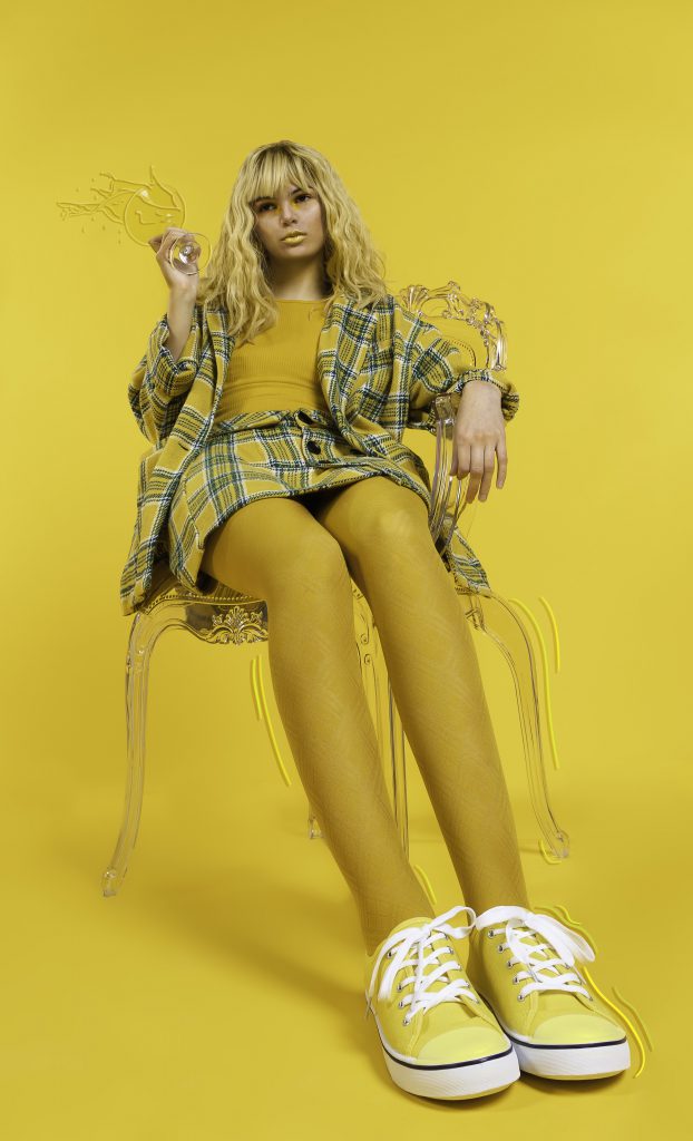 A completely yellow image of a woman sitting in a clear chair