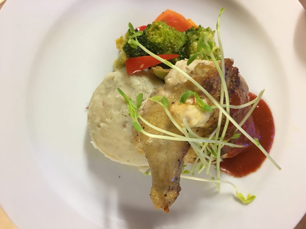 Chicken supreme with mashed potatoes and seasonal vegetables on a white plate