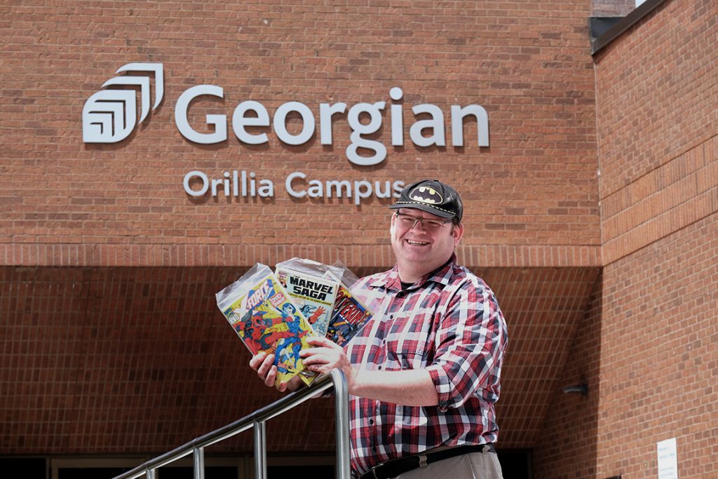 Person holds up comic books in front of a building.