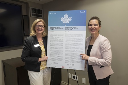 Dr. MaryLynn West-Moynes and The Honorable Kirsty Duncan stand on either side of the NSERC dimensions charter
