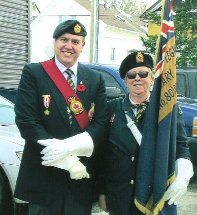 Two veterans in military attire at Remembrance Day ceremony pose together