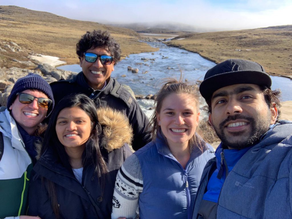 3 Georgian College co-op students and their colleagues on a hike beside a river in Iqaluit.