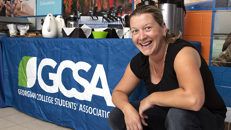 Georgian-Muskoka-Practical-Nursing-student-Angela-Tremblay-smiles-at-camera-while-posing-in-front-of-GCSA-banner