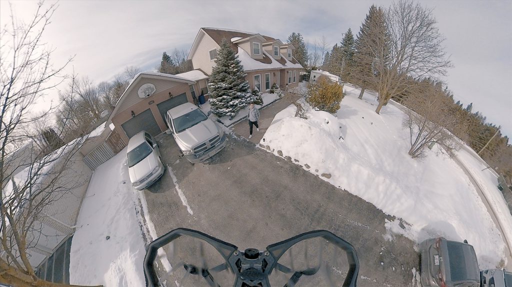An overview shot of a drone coming down to a house