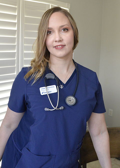 A young blonde female wearing blue nursing scrubs