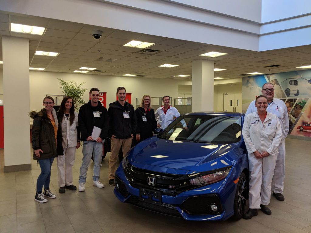 A group of 8 Georgian College students and HCM employees stand around a Honda Civic