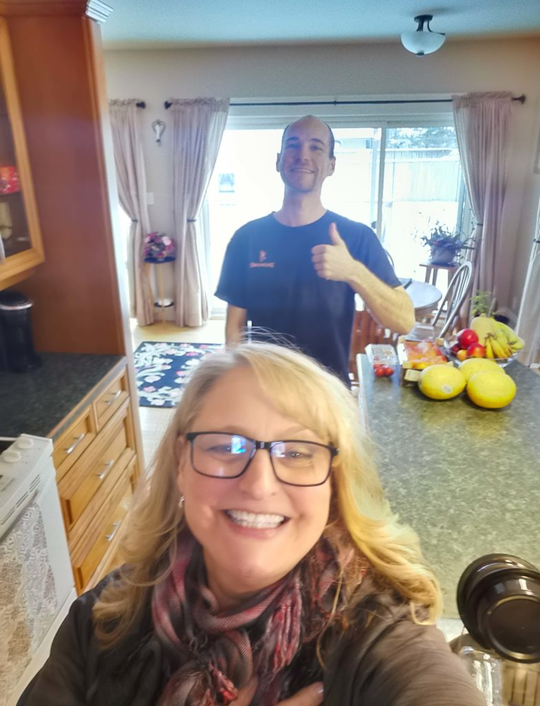 A woman takes a selfie in her kitchen with her male student tenant