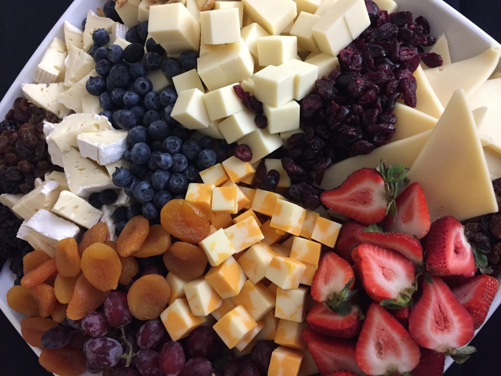 Tray of assorted cheeses, strawberries, blueberries, and apricots