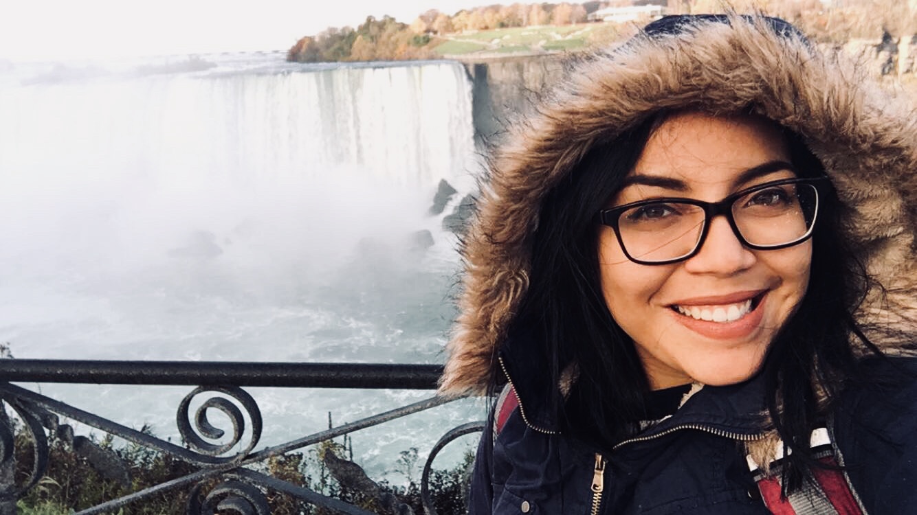 A woman standing in front of Niagara Falls, smiling