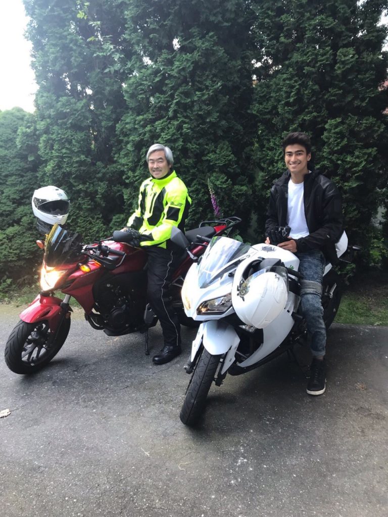 Two smiling males sitting on motorcycles outside