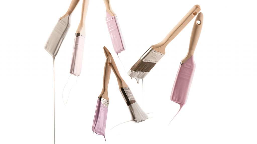Paint brushes on white background with pink, ivory and taupe paint on them