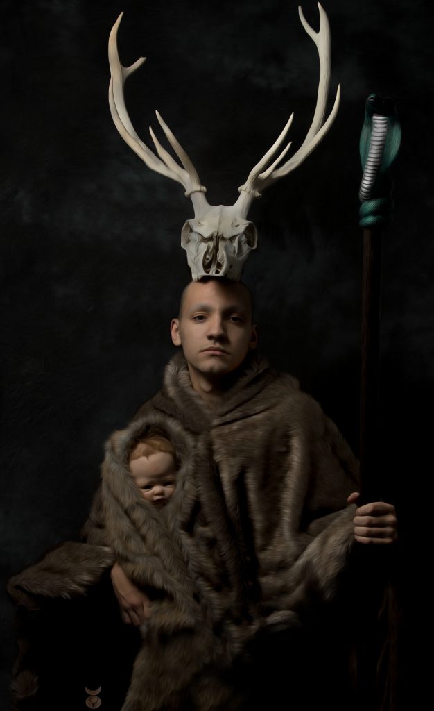 Man with antelope skull on head holding a baby with both in fur