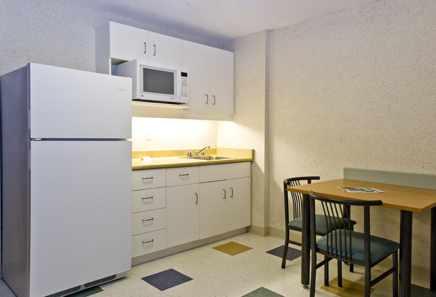 Kitchenette with fridge, table, chairs, microwave, sink, and cupboards