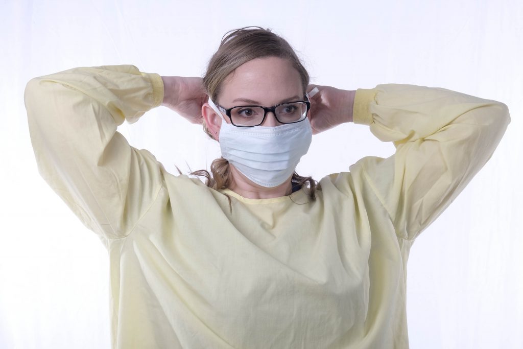 Lisette Verzijlenberg wearing scrubs, glasses as she ties on a medical mask