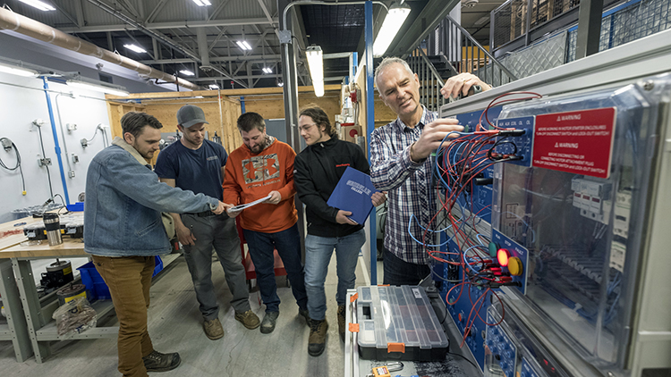 Male-Electrical-Techniques-instructor-teaches-three-male-students-in-Skilled-Trades-Centre