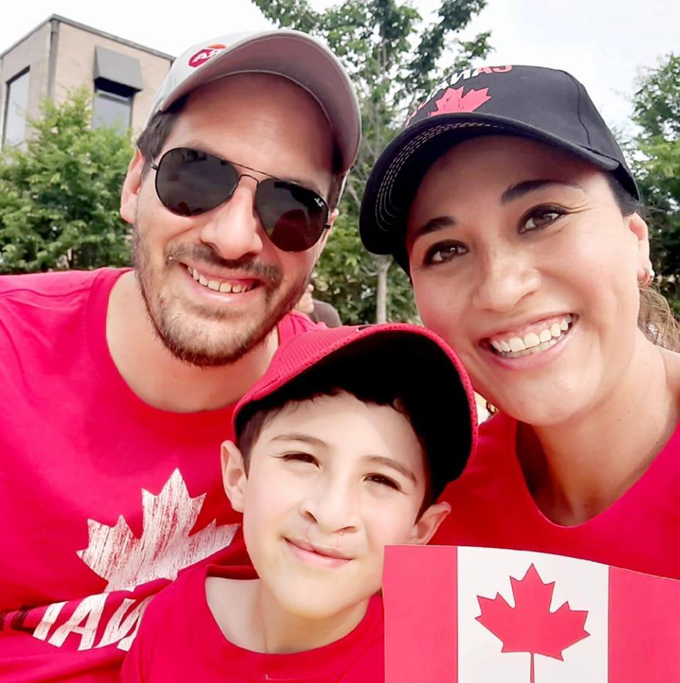 Two adults and a child all dressed in red and white for Canada Day smile for a selfie.
