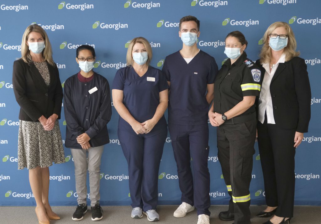 Minister Dunlop and MaryLynn West-Moynes, President and CEO of Georgian, stand with four Georgian Health, Wellness and Sciences students