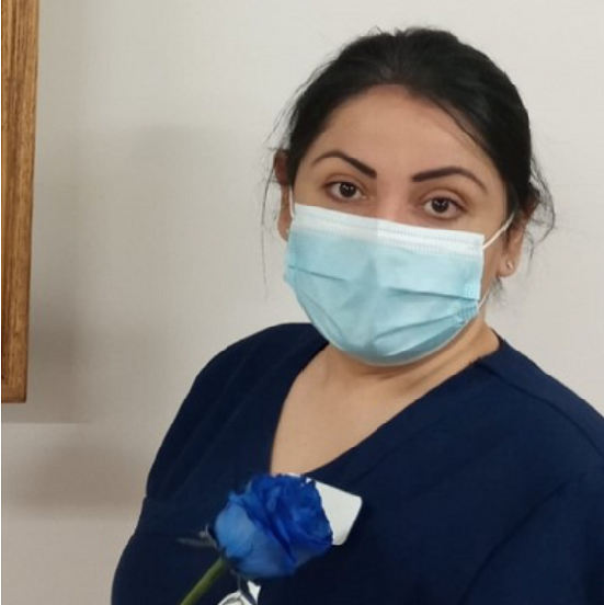 Nina Shirin Sheik in scrubs, holding a blue rose