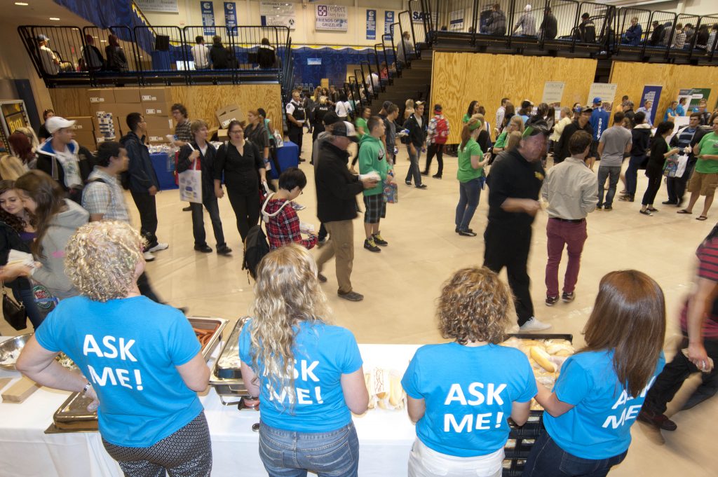 A row of ask me volunteers in the Barrie Campus gym, with students in the background