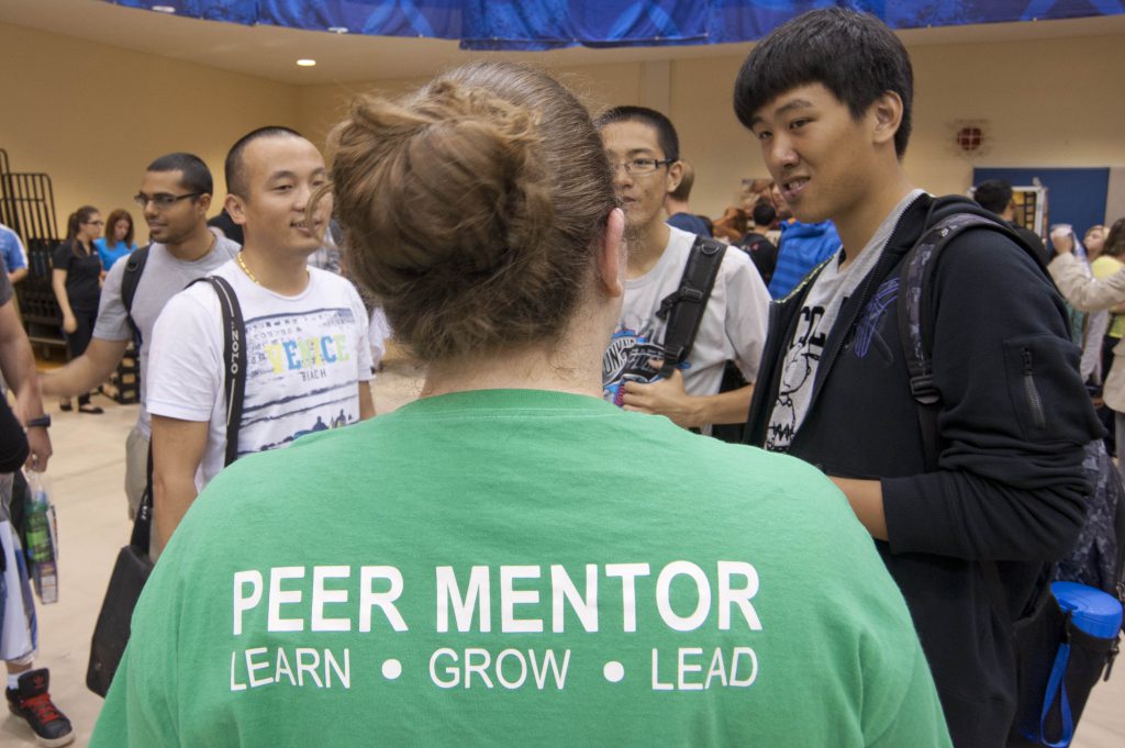 A peer mentor's back, with students asking her questions