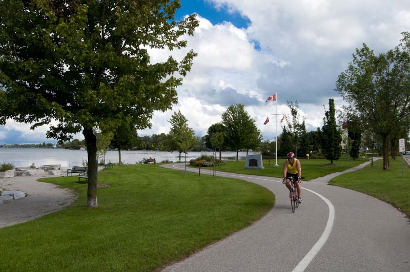 A man riding a bike on a paved trail on the waterfront in Orillia, Ontario