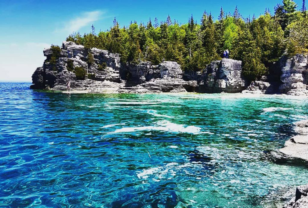 Clear blue water splashing on the rocks at the Grotto in Tobermory, Ontario