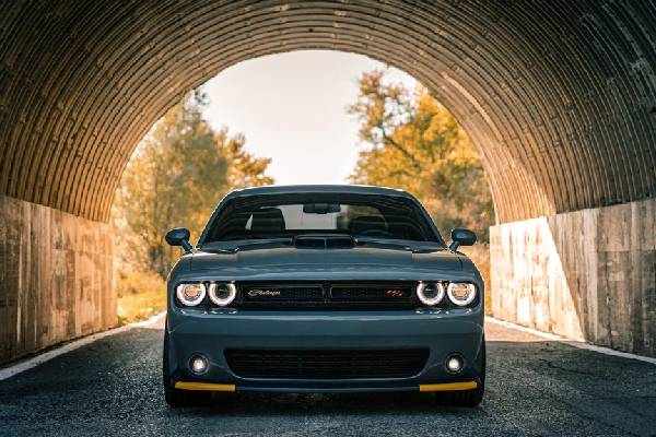 a photography of a Dodge charger inside a tunnel with landscape scenery in the background