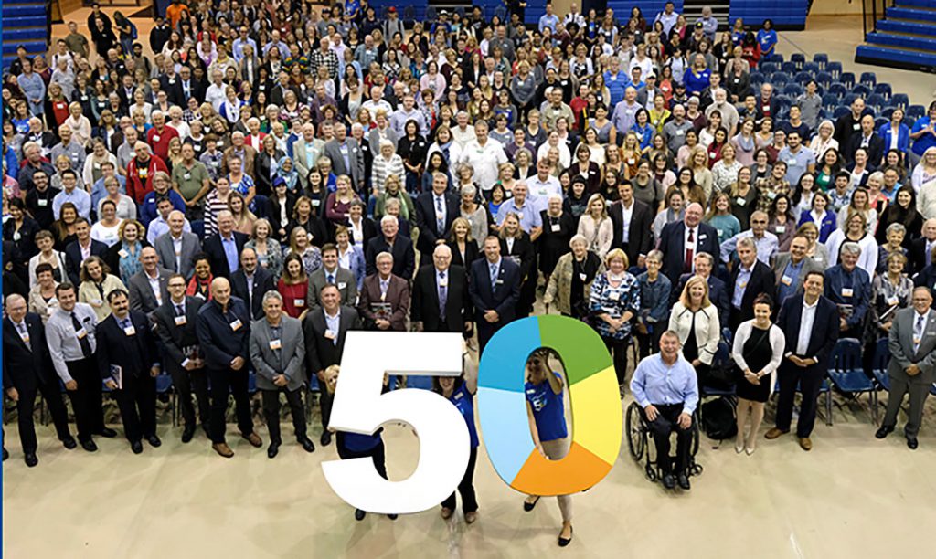 a large group of people standing in front of a big 50