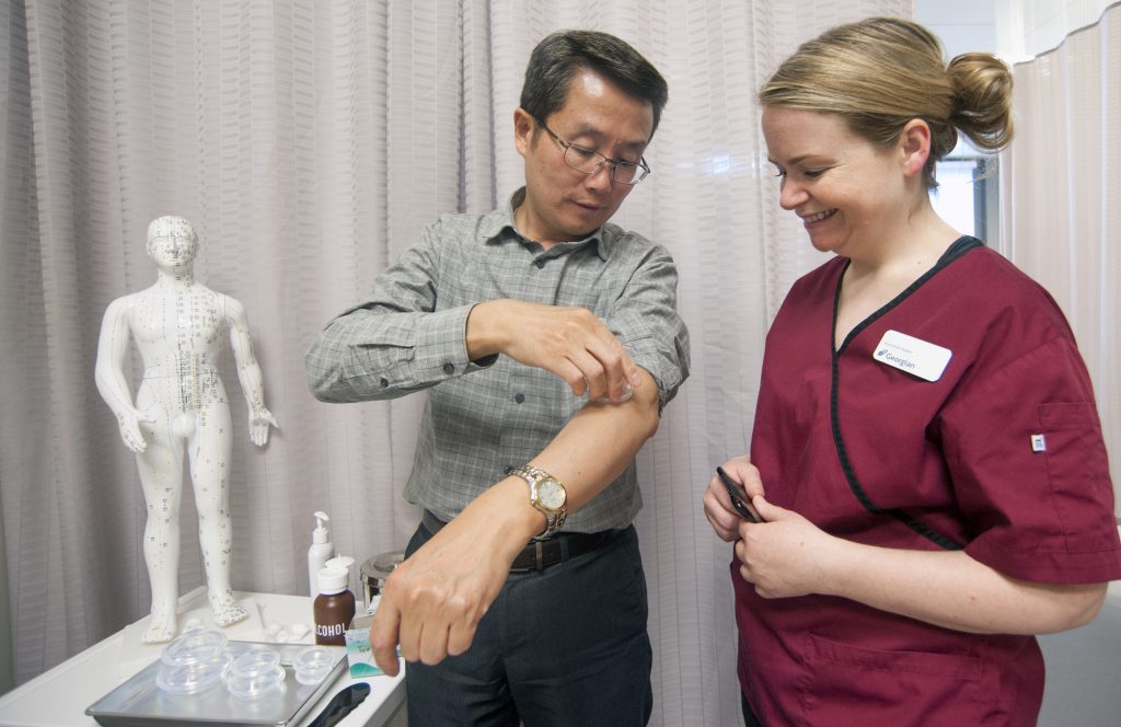 Professor showing student how to insert acupuncture needles