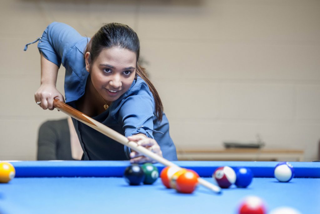 Young female student playing pool in The Den