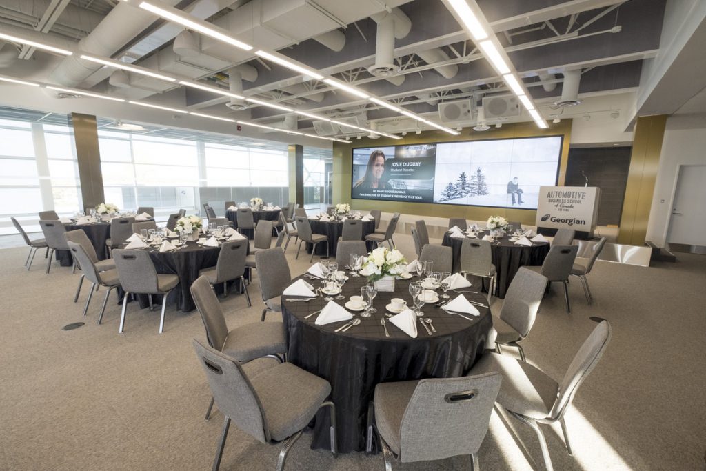 An open event space set up with dining tables and chairs, set for meal service.