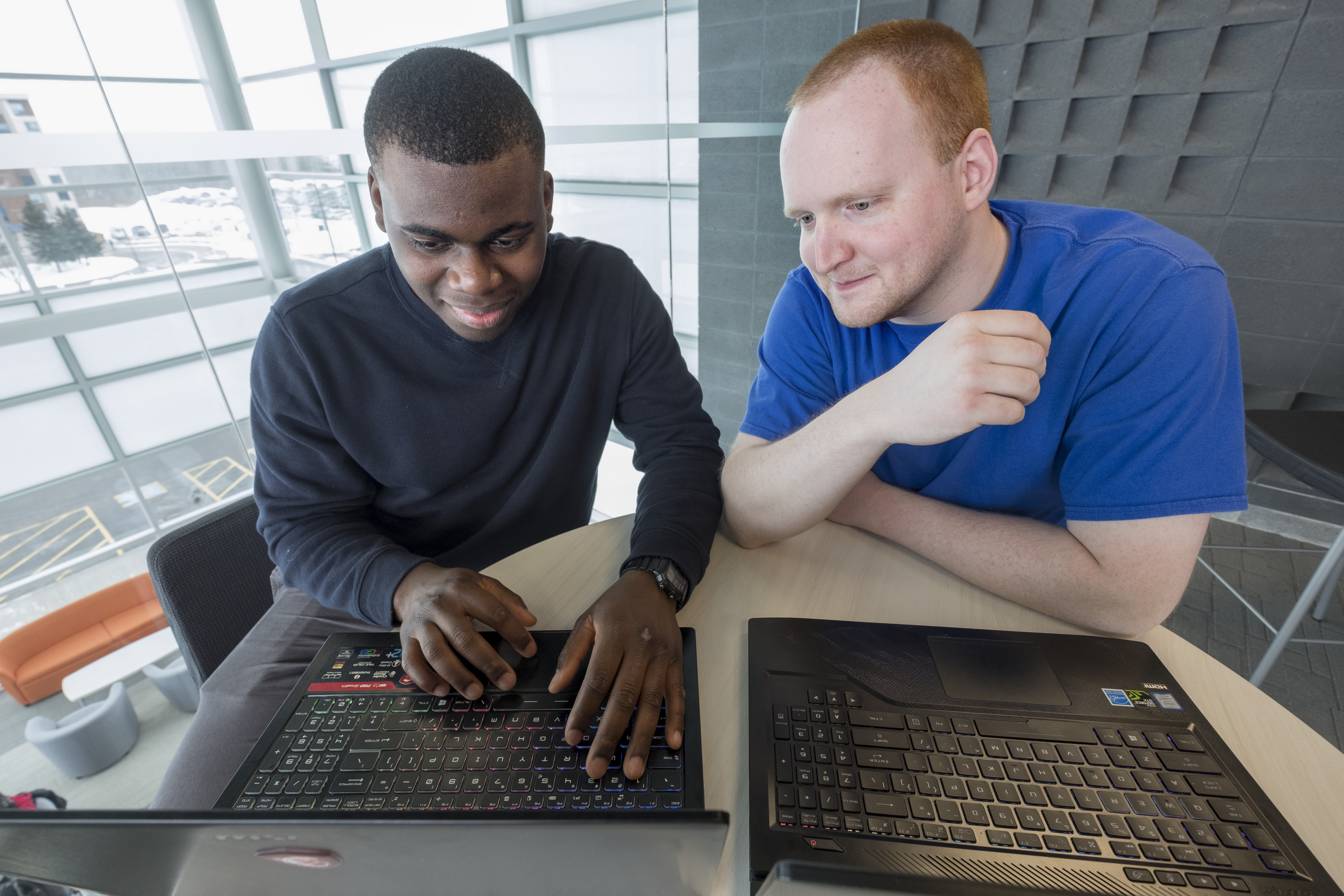 2 male students working on their laptops