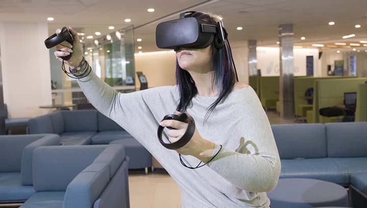 A woman wearing a virtual reality head set and holding hand controls