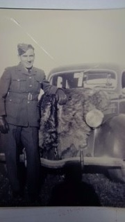 Black and white photo of solider posing near old vehicle